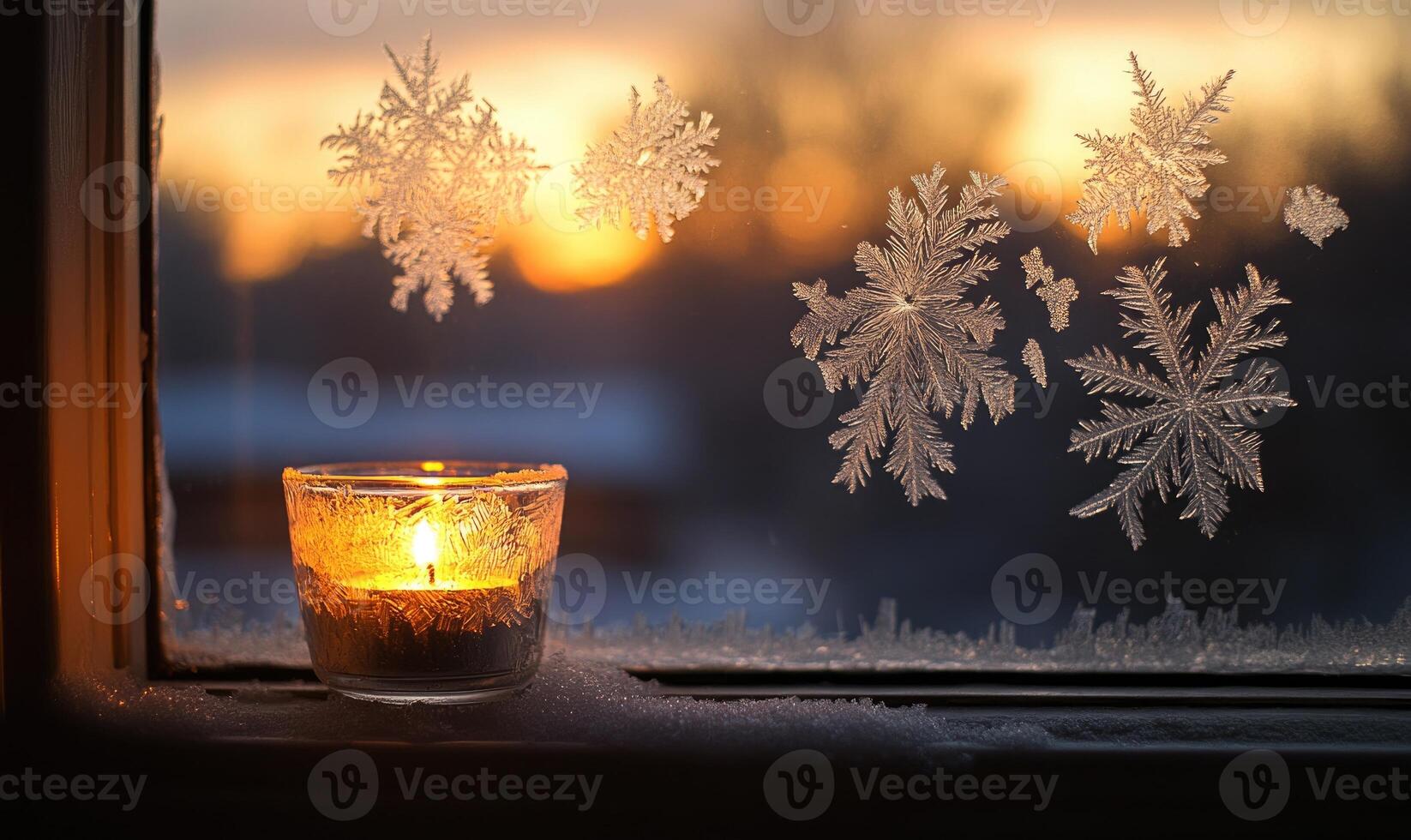 A candle is lit in a glass jar with snowflakes on the window photo