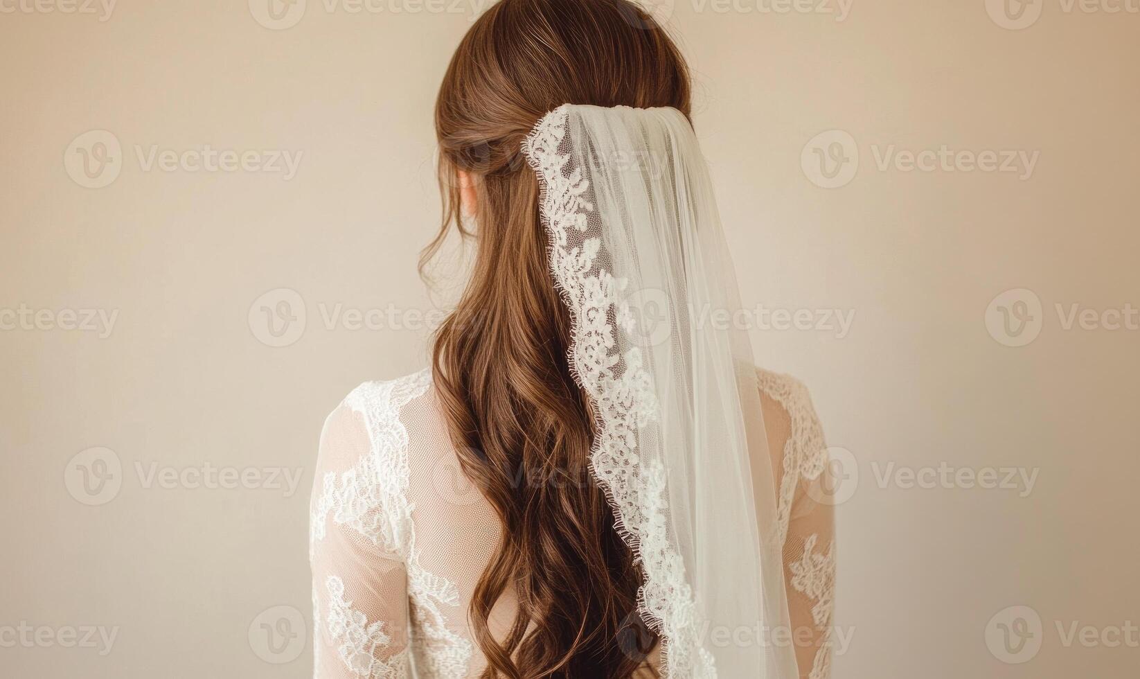 A woman with long brown hair wearing a white lace veil photo