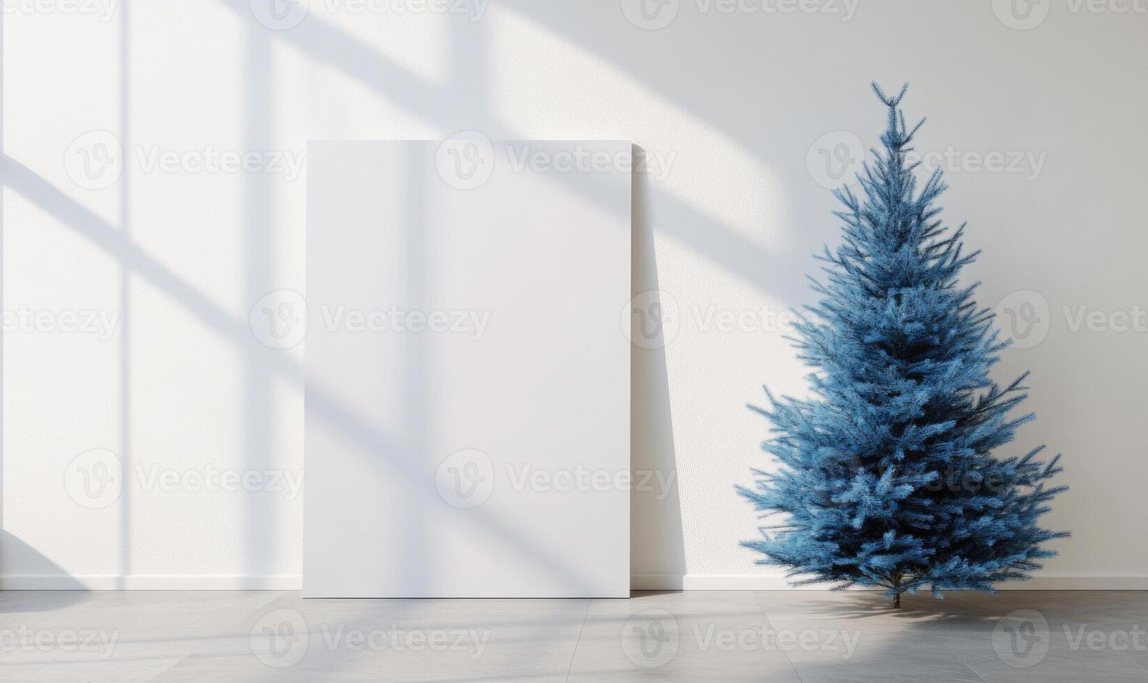 A blue Christmas tree sits in front of a white wall photo
