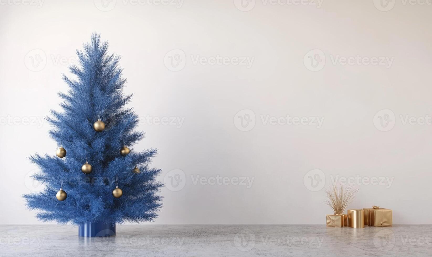 A blue Christmas tree with gold ornaments sits in front of a white wall photo