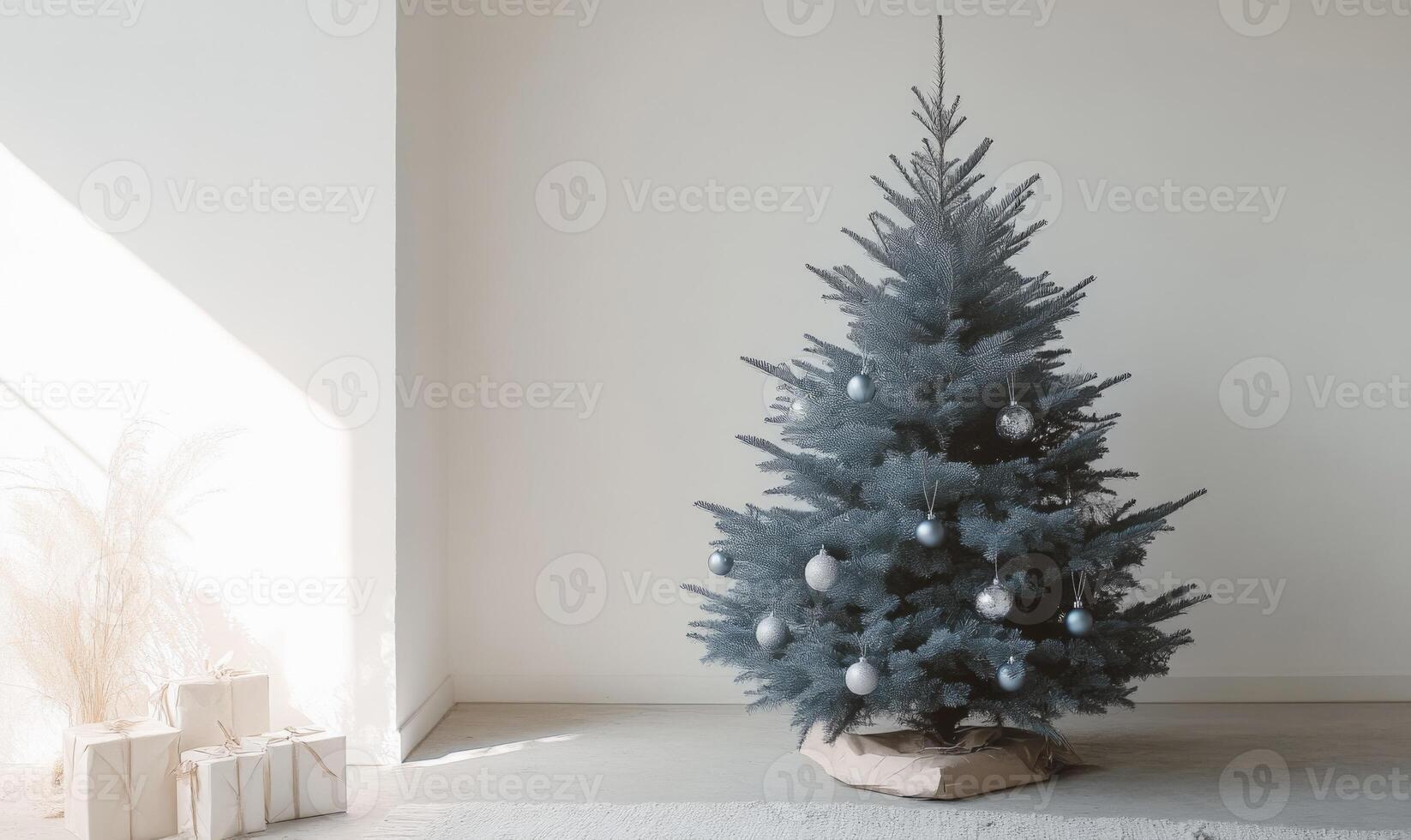 A large blue Christmas tree with many ornaments sits in a room with a white wall photo