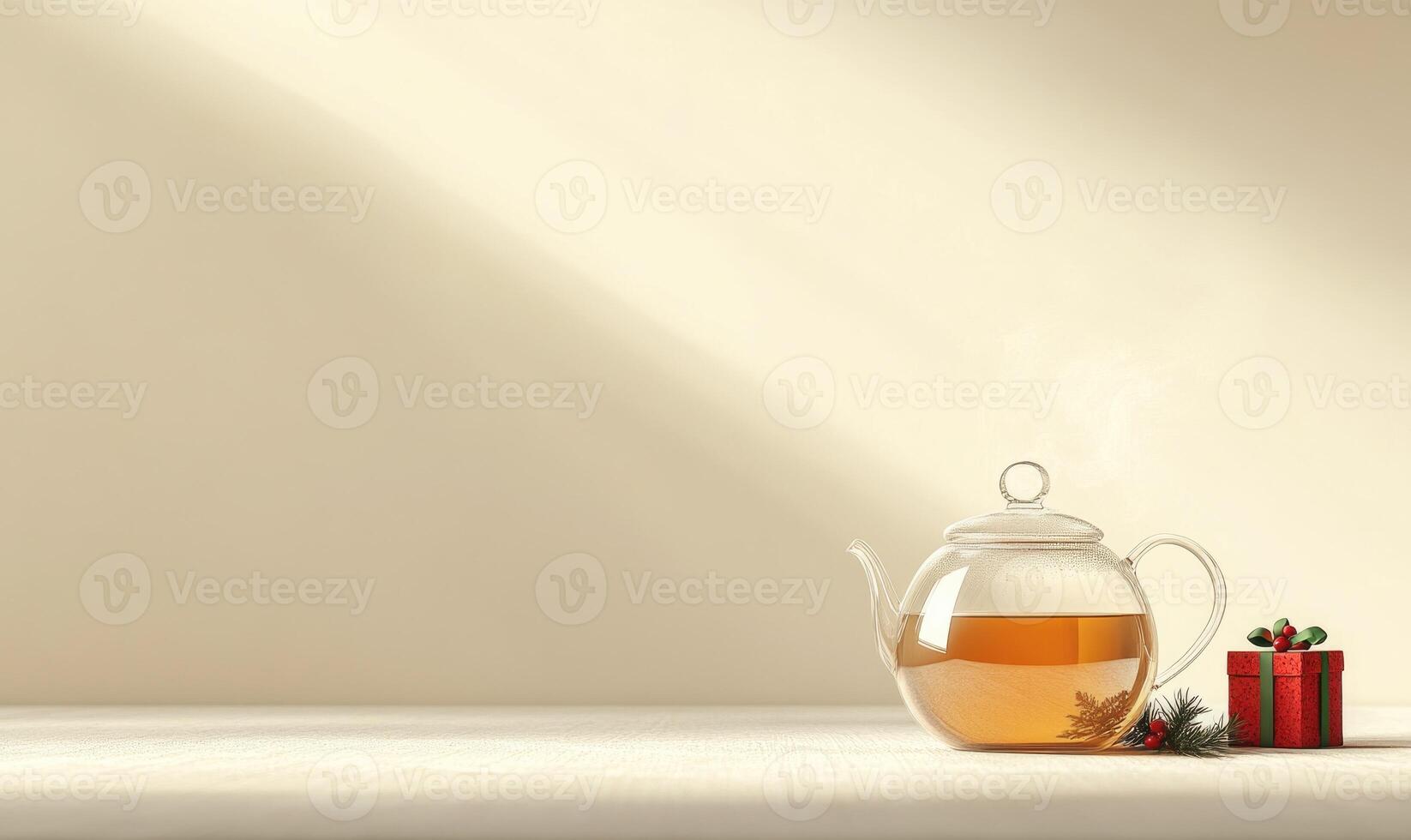 A glass tea kettle sits on a table next to a red box photo