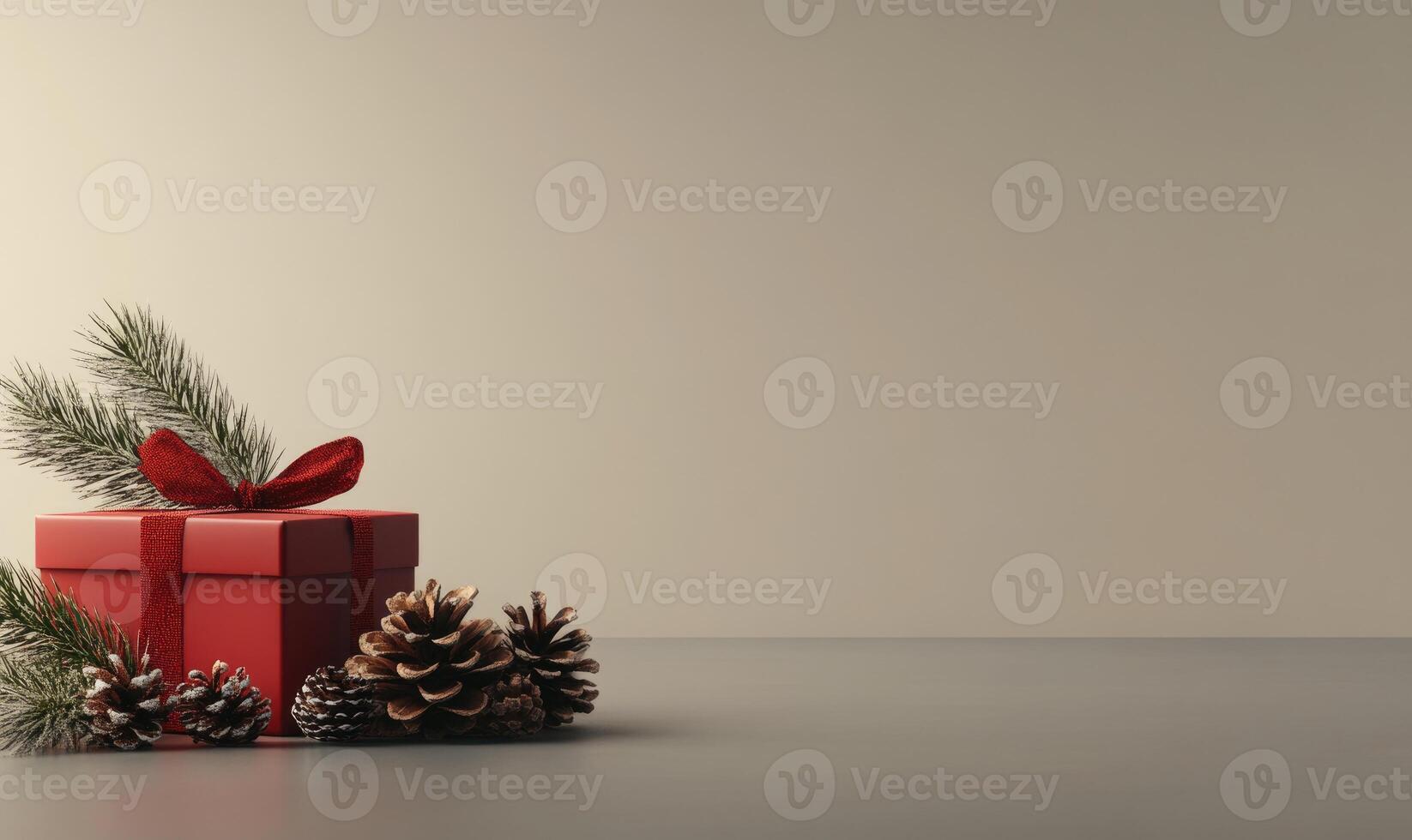 A red box with a red ribbon sits on a table with pine cones photo