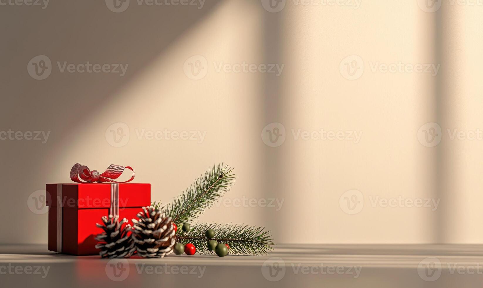A red box with a ribbon sits on a table next to pine needles and berries photo
