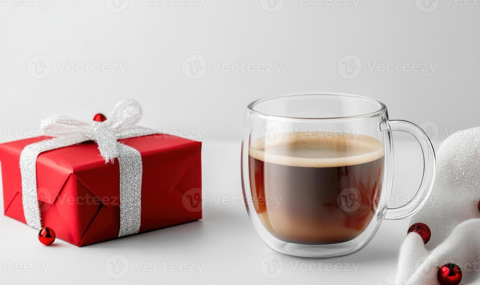 A red box with a white bow sits on a table next to a cup of coffee photo