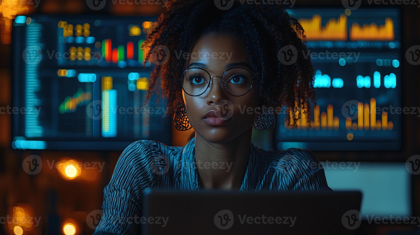 African woman analyzing data laptop with financial charts on a screen multitasking between tablet and desktop in a hybrid office setup photo
