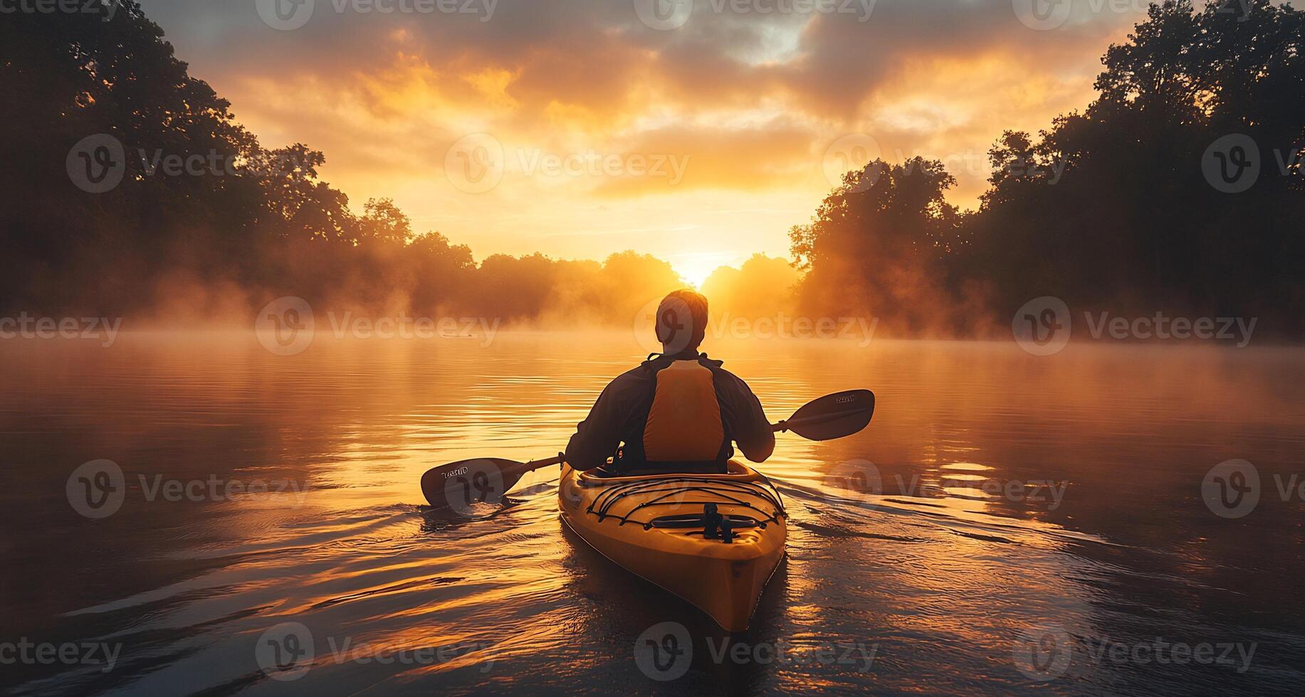 Man rowing a kayak across a calm lake at sunrise water rippling behind him wearing outdoor gear and life vest mist rising from the water photo