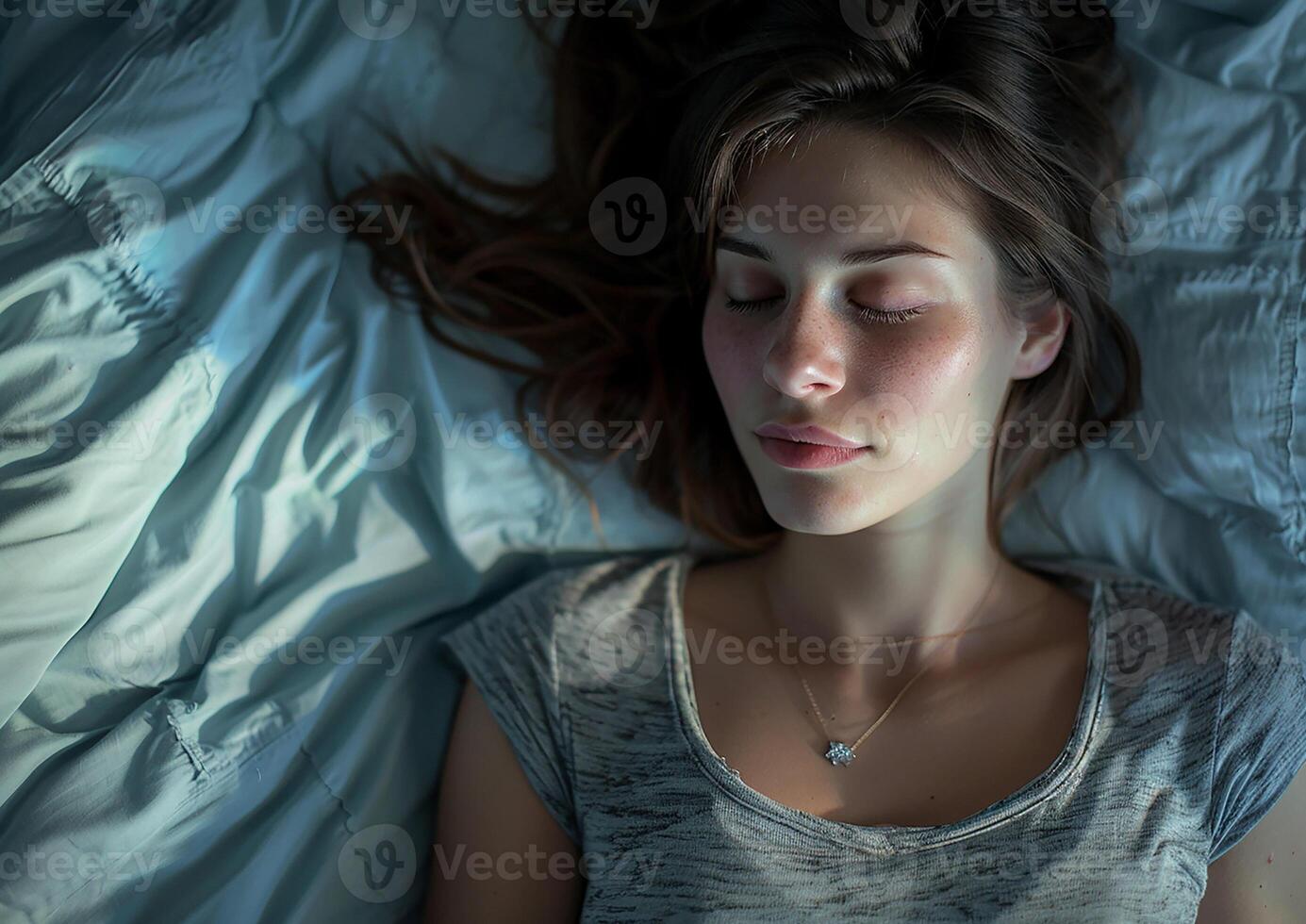 Young woman in a deep sleep, seen from a top-down perspective on her bed photo