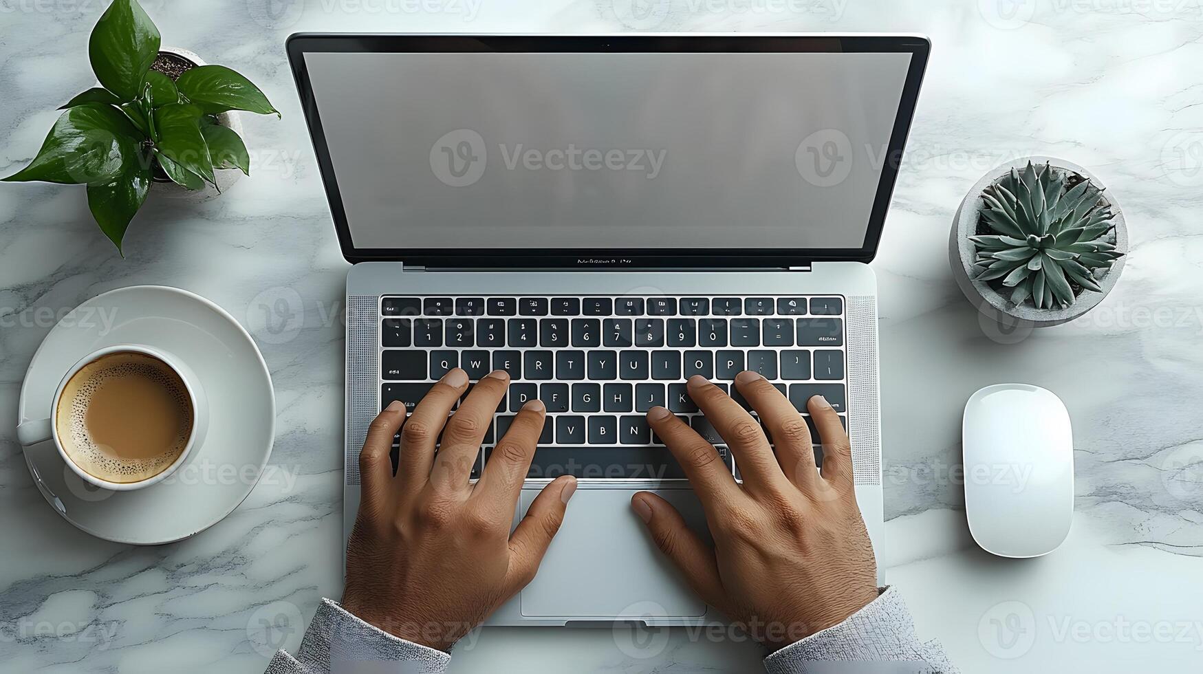 Close-up of hands typing on a laptop at a modern desk, with a cup of coffee and a small plant nearby. photo