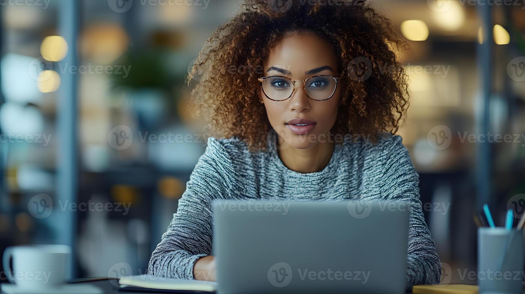 Close-up of a woman typing on her laptop in a tidy workspace, with a notebook and pen within reach. photo