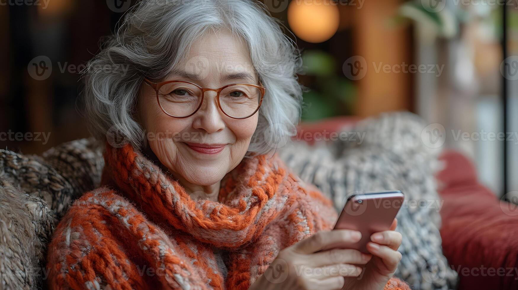 Cheerful senior woman seated on a sofa, using her smartphone to read a message. The bright, comfortable living room enhances the joyful atmosphere. photo