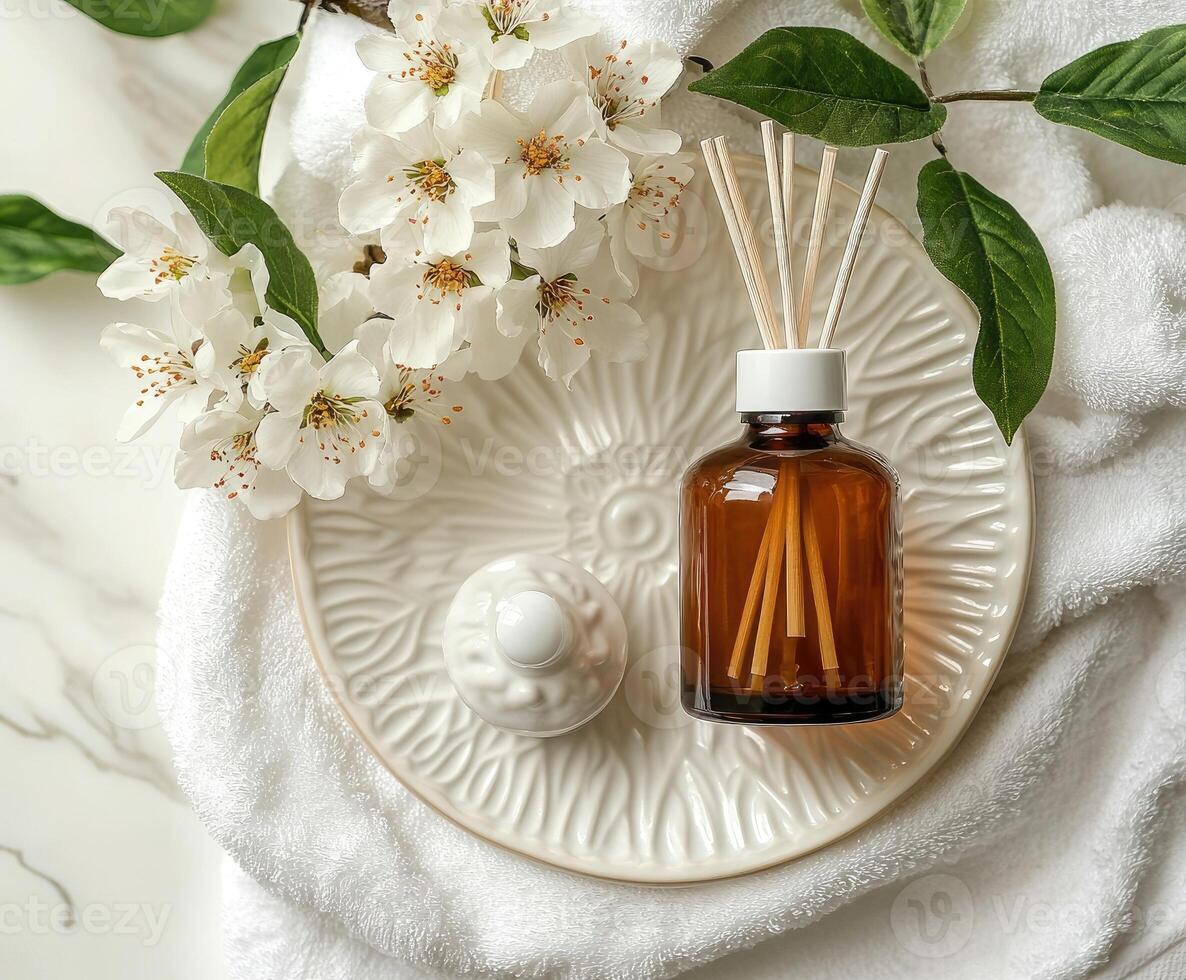 Aromatherapy setup with flowers and oil on white towel. photo