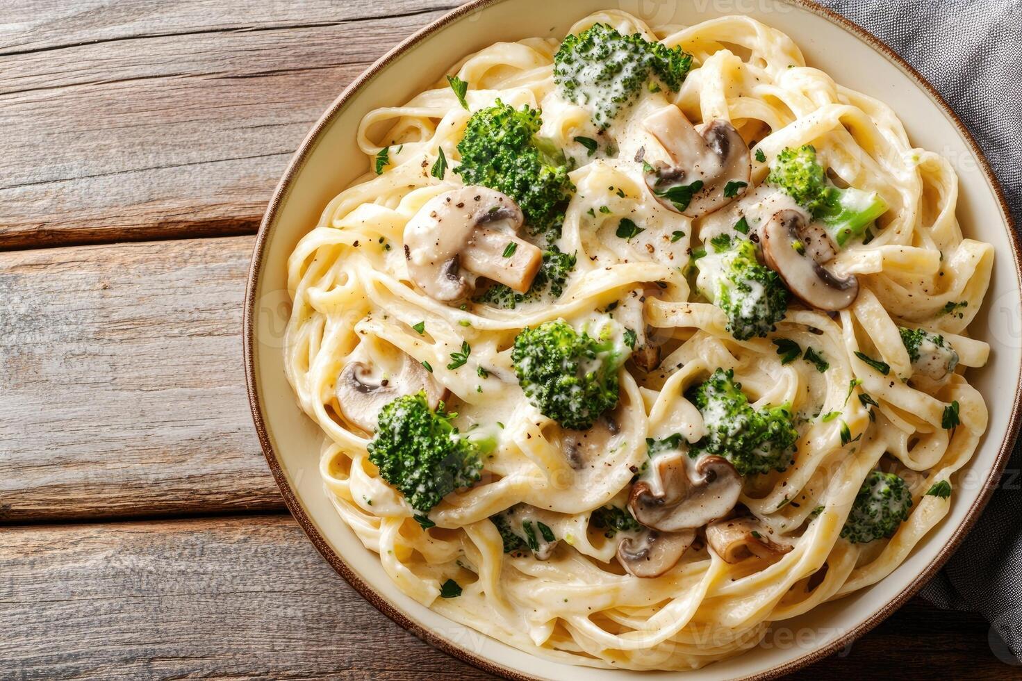 Tagliatelle pasta with creamy sauce, mushrooms, and broccoli served in a bowl photo
