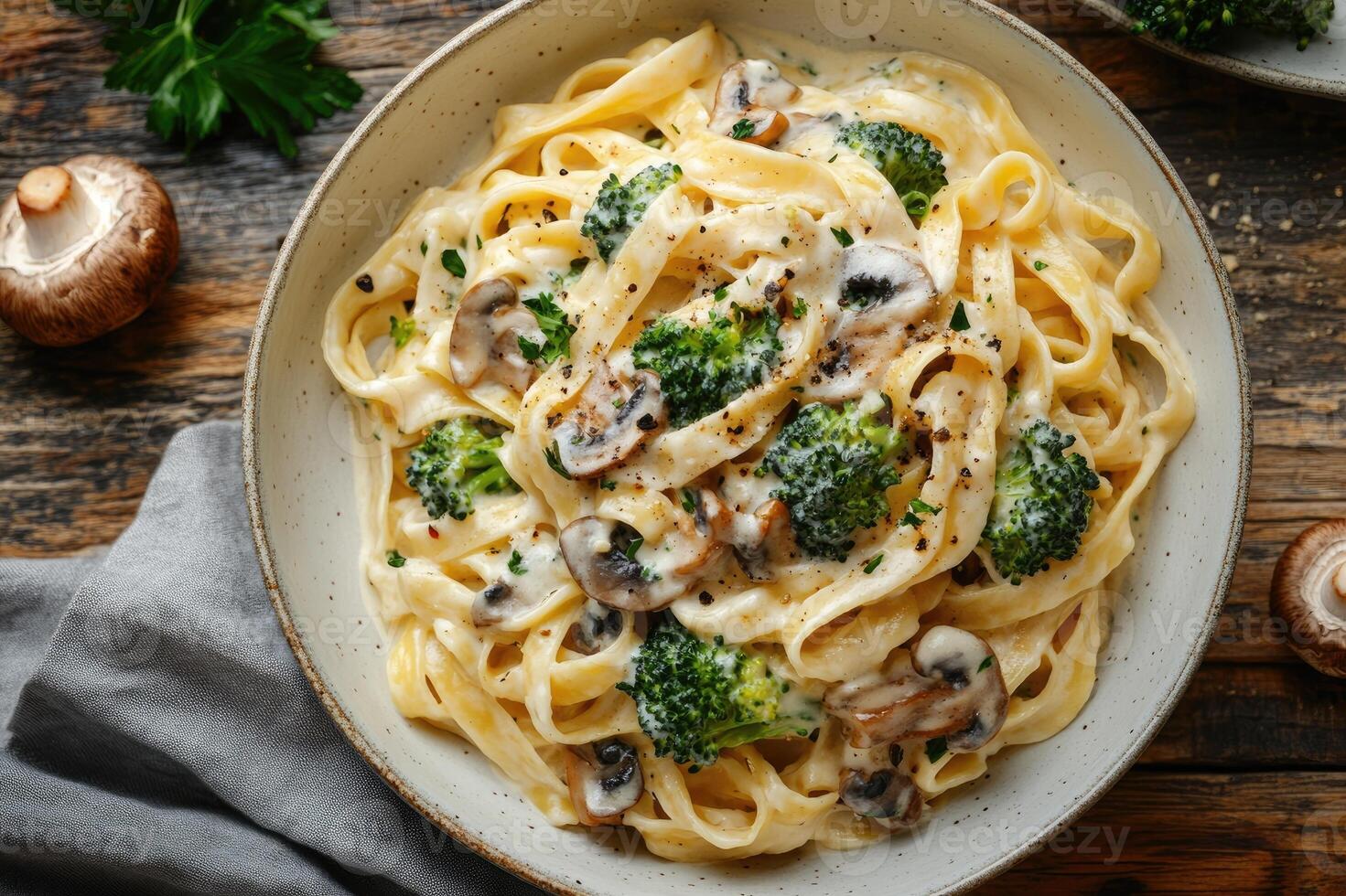 Tagliatelle pasta with creamy sauce, mushrooms, and broccoli served in a bowl photo