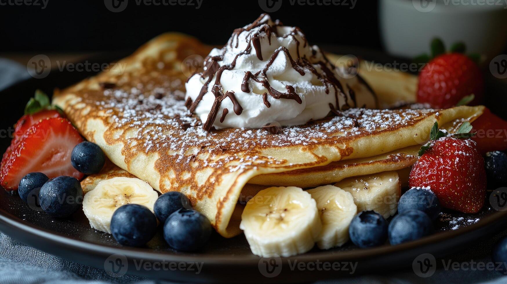 Delicious homemade crepes filled with banana and topped with strawberries, blueberries and whipped cream photo