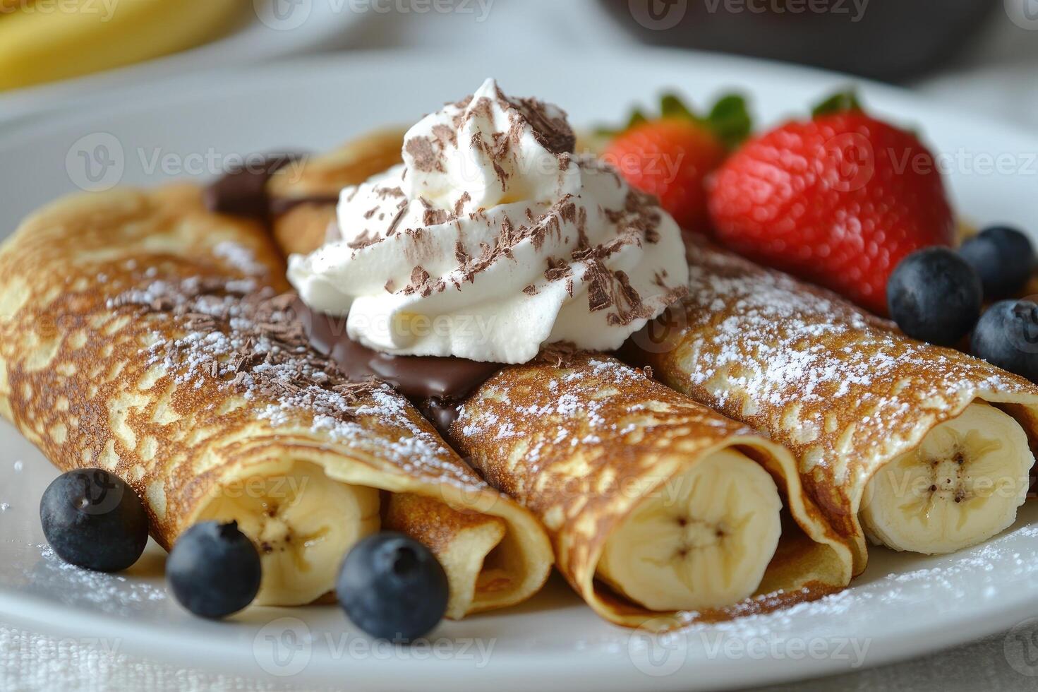 Delicious homemade banana pancakes being topped with whipped cream and chocolate photo