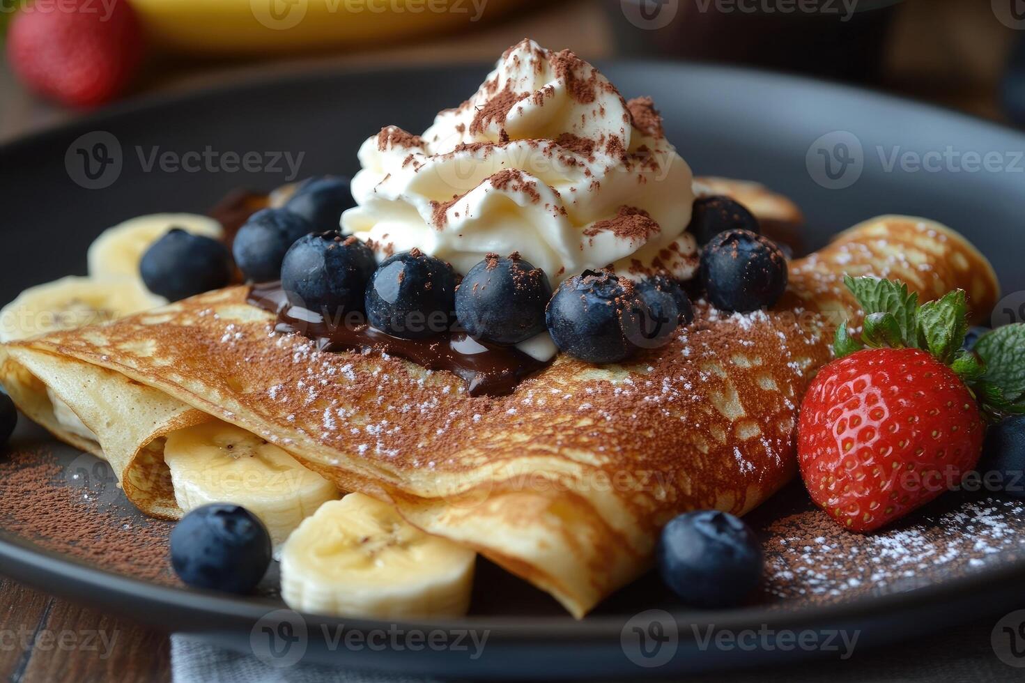Delicious homemade banana pancakes being topped with whipped cream and chocolate photo