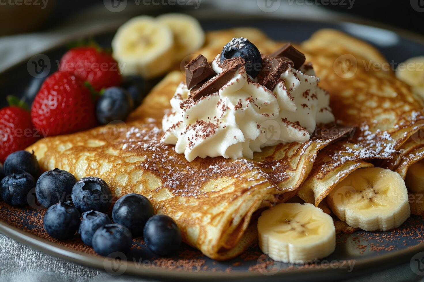 Delicious homemade banana pancakes being topped with whipped cream and chocolate photo