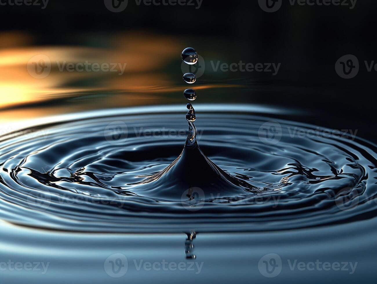 Water droplet making concentric ripples on dark water surface photo