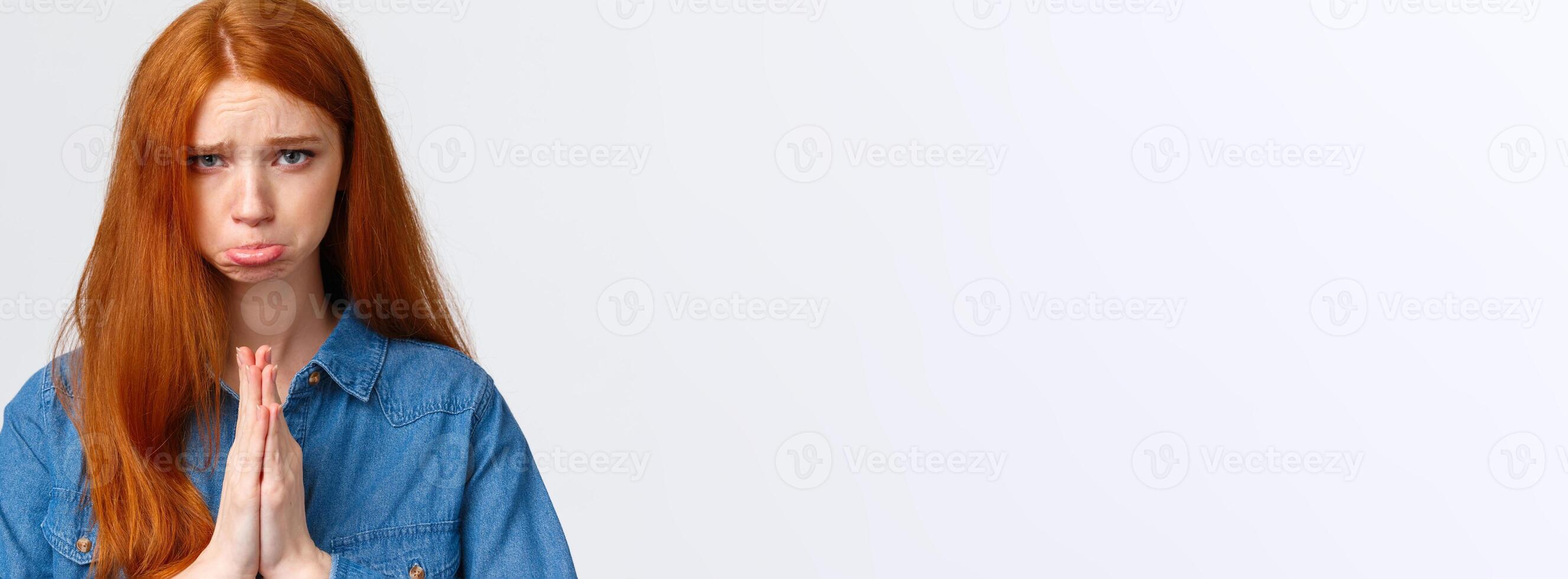 Pretty please. Close-up portrait sad, sulking cute redhead girl feeling guilty begging apology, pouting and frowning hopeful look camera, press hands together in pray, pleading over white background photo