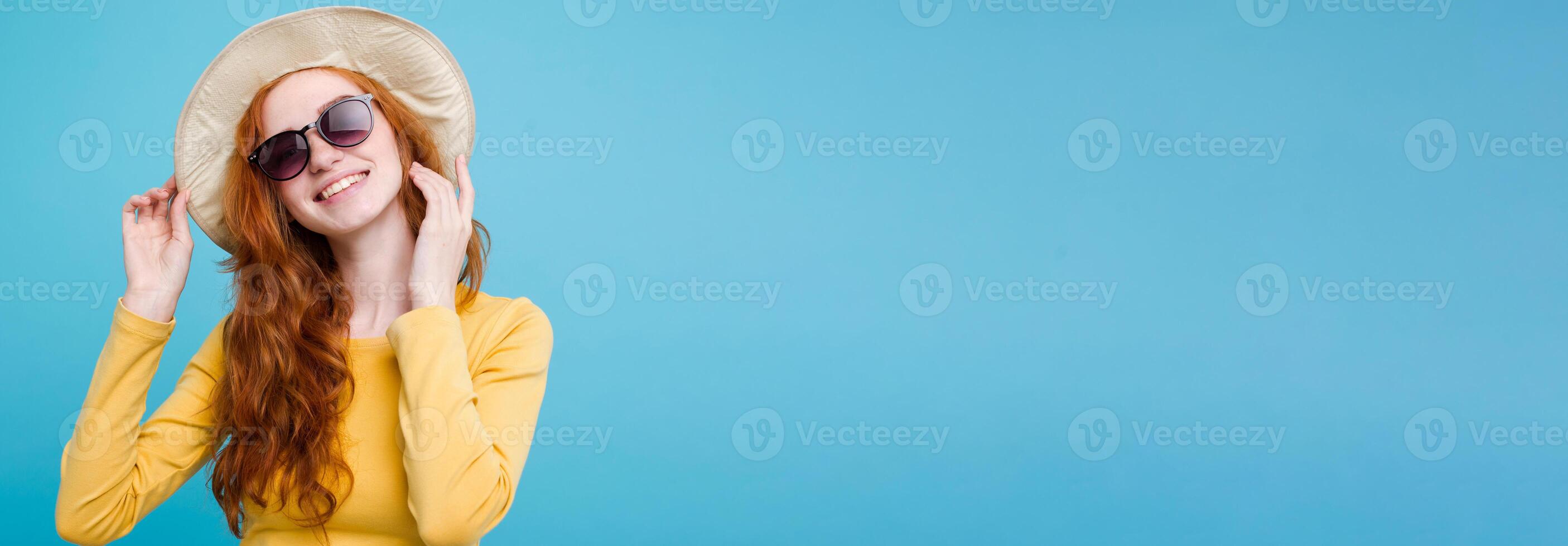 Travel concept - Close up Portrait young beautiful attractive redhair girl wtih trendy hat and sunglass smiling. Blue Pastel Background. Copy space photo