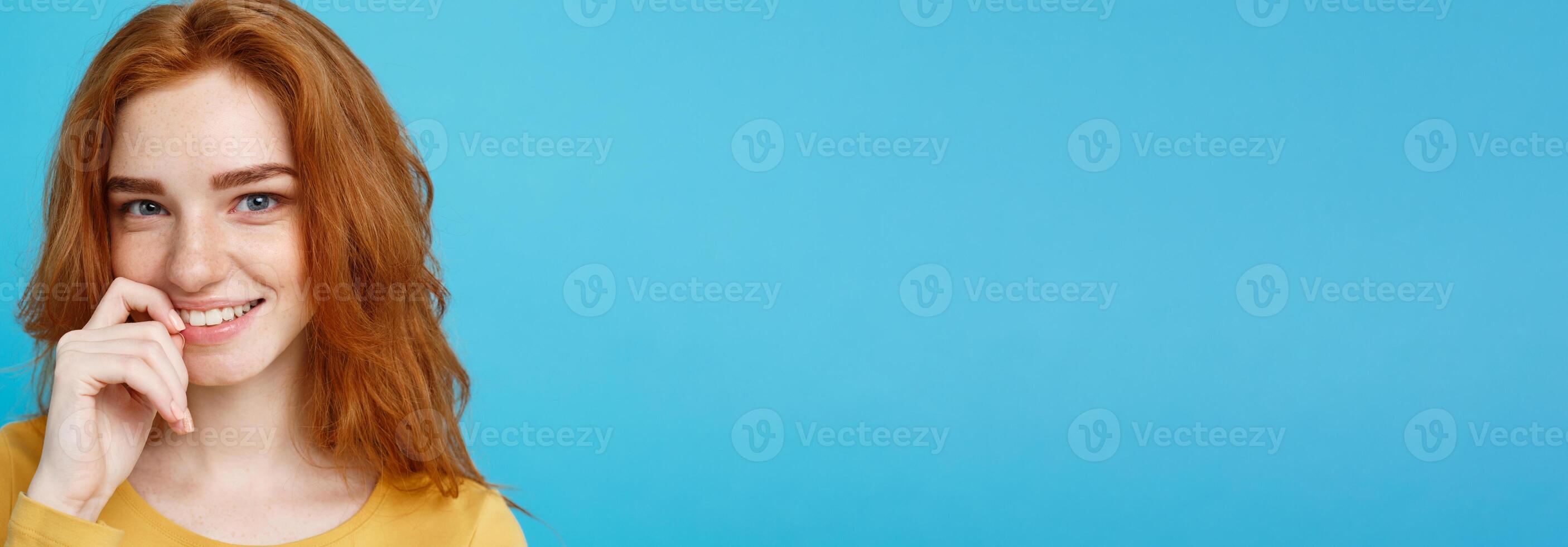 Headshot Portrait of happy ginger red hair girl with freckles smiling looking at camera. Pastel blue background. Copy Space. photo