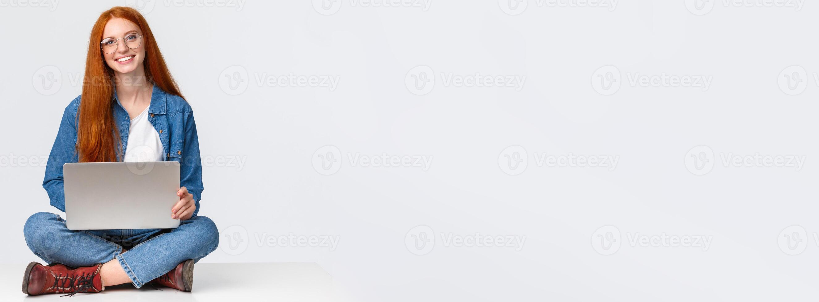 Attractive charismatic redhead caucasian female sit on floor with crossed legs, holding laptop laps, working on fresh air, writing new program, freelancing over white background photo