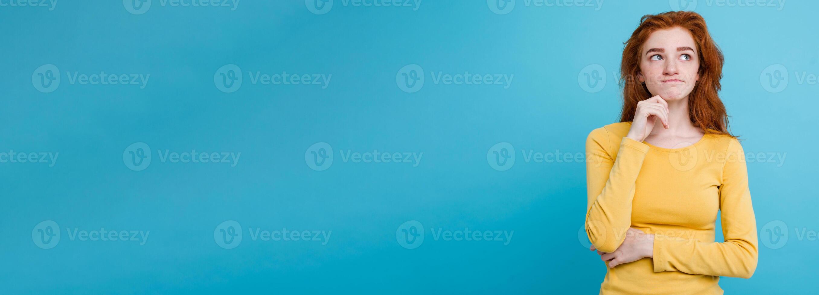 Portrait of happy ginger red hair girl with freckles smiling looking at camera. Pastel blue background. Copy Space photo
