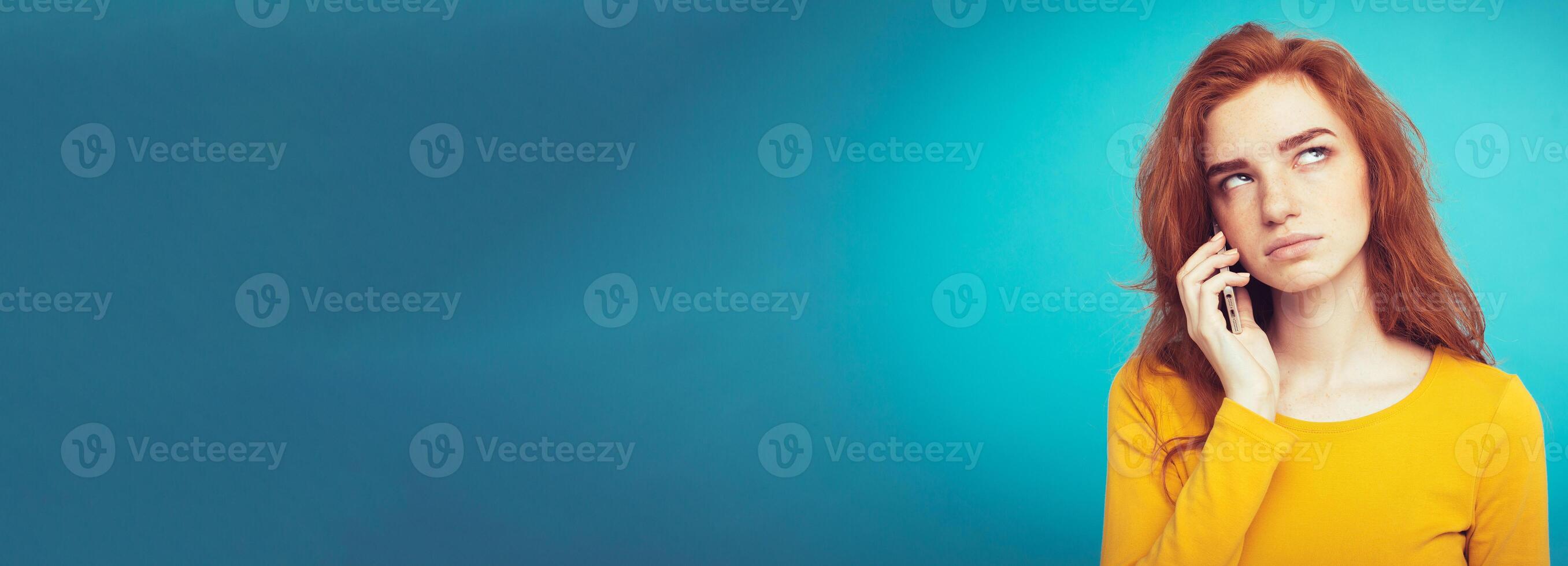 Lifestyle concept - Portrait of ginger red hair girl with shocking and stressful expression while talking with friend by mobile phone. Isolated on Blue Pastel Background. Copy space photo