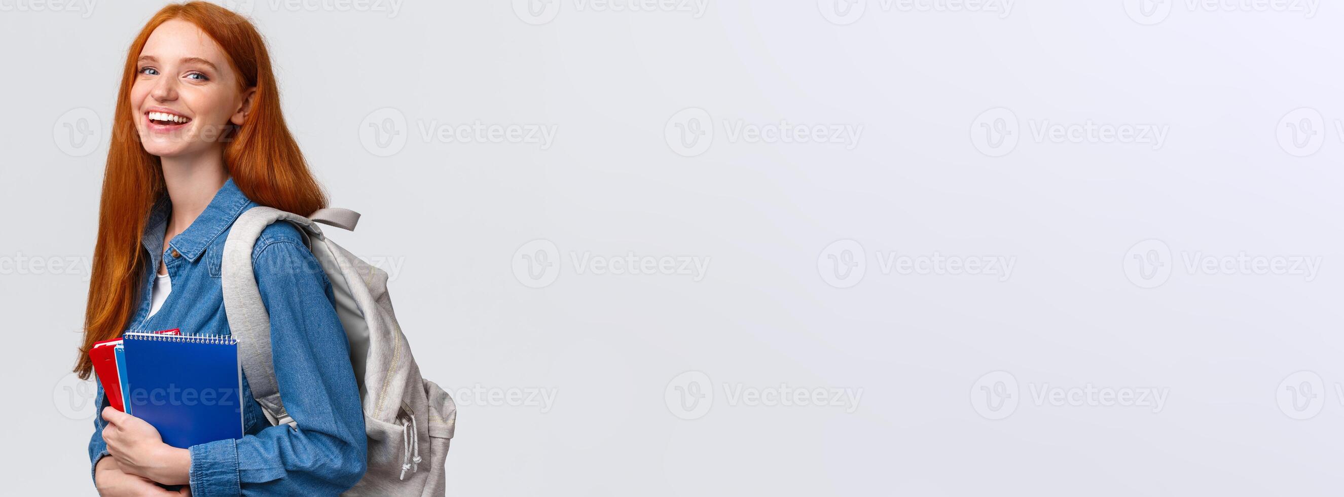 Students, education and studying concept. Lovely charismatic redhead foxy girl with backpack, notebooks and study books, standing white background, smiling joyful looking camera photo