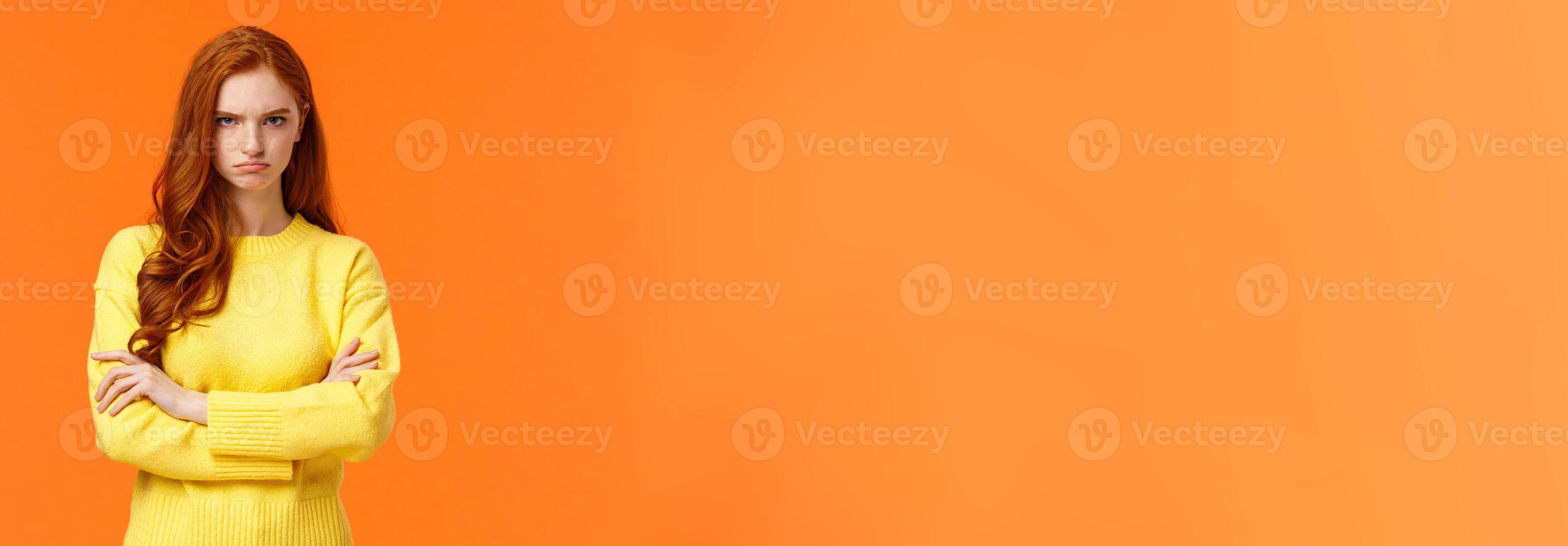 I am mad. Offended sulky cute and timid redhead curly girl, cross arms chest, sulking angry and tensed, frowning stare disappointed someone sad rude words, standing orange background insulted photo