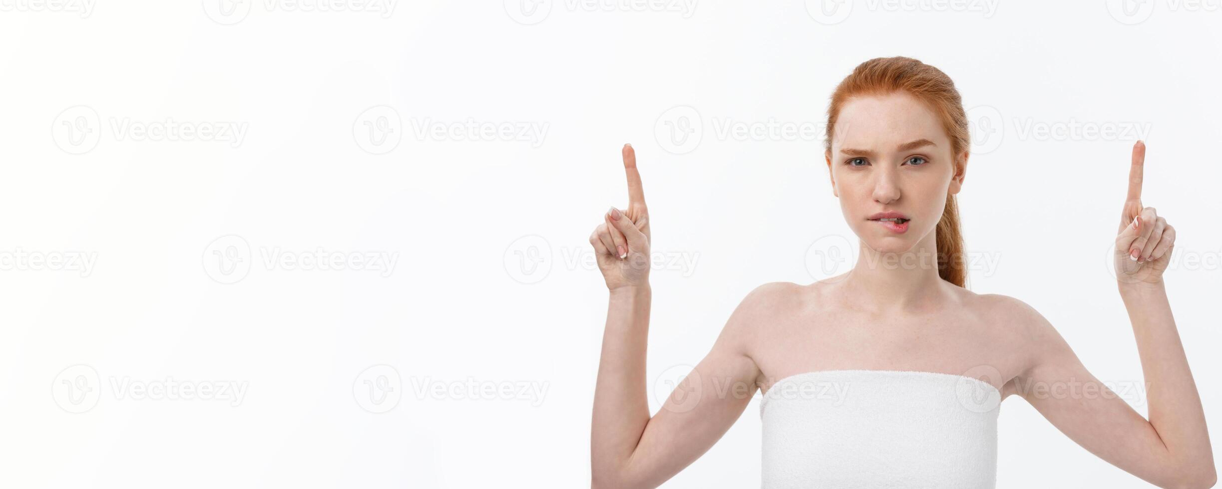 Portrait of young redhead female with perfect freckled skin showing something interesting at copy space wall for your advertising content. photo