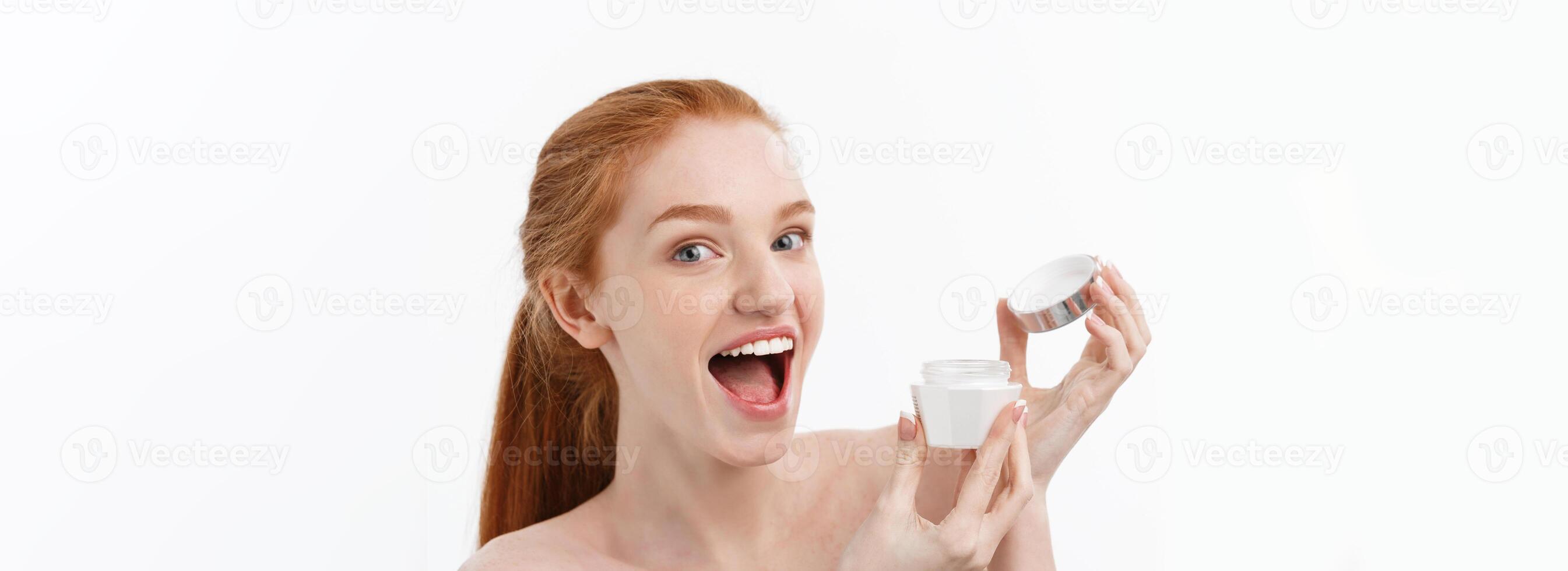 portrait of beautiful woman smiling while taking some facial cream isolated on white background with copy space. photo