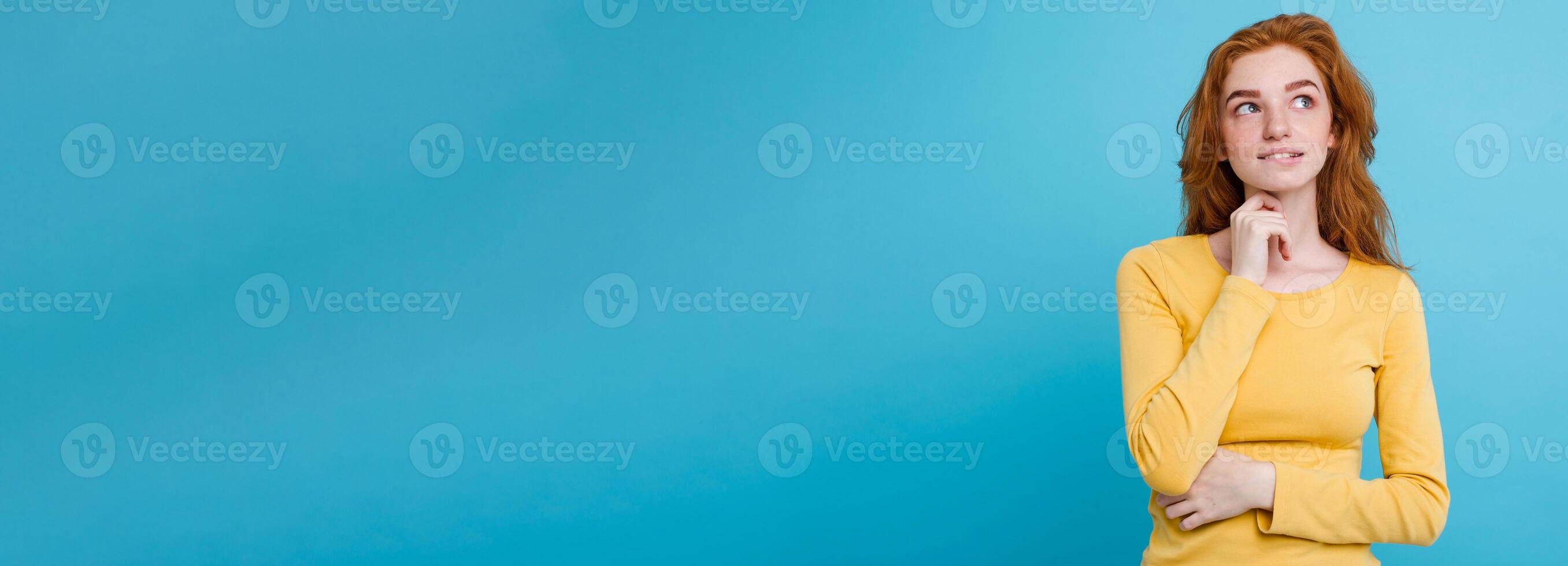 Portrait of happy ginger red hair girl with freckles smiling looking at camera. Pastel blue background. Copy Space photo
