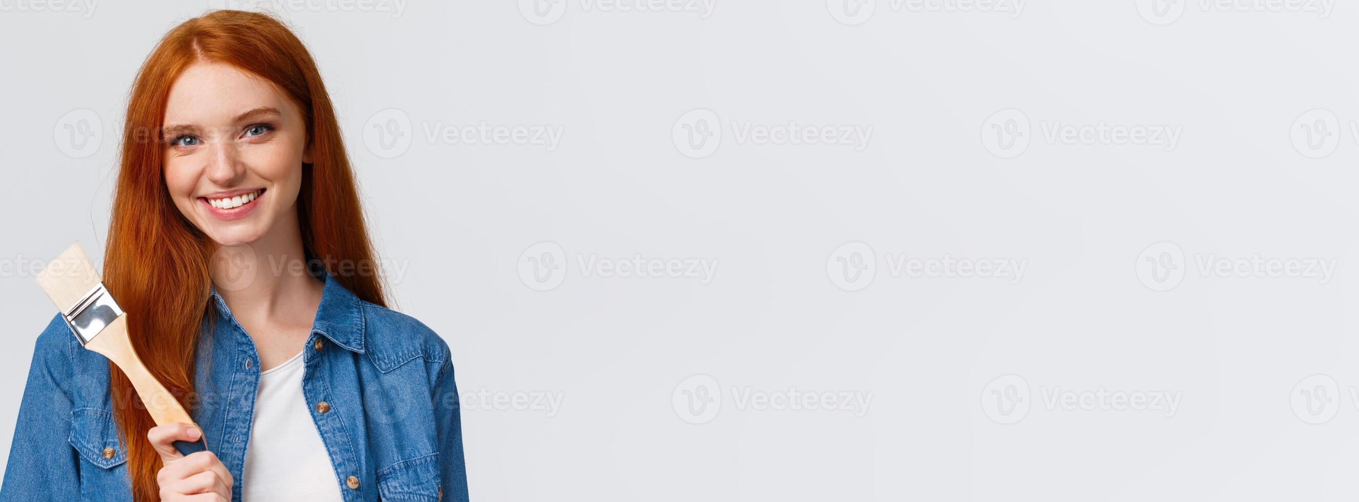 Close-up portrait talented and creative cute redhead girl with blue eyes like drawing, attend art courses, holding painting brush, consider paint walls new color, smiling confident, white background photo