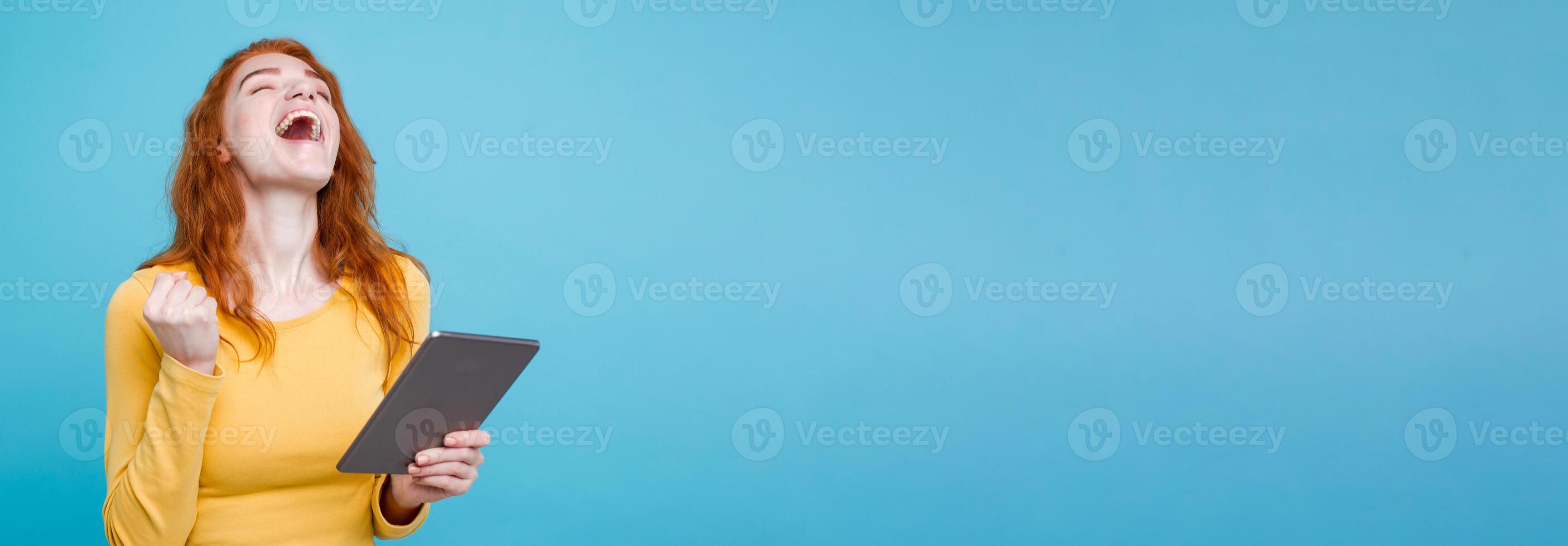People and Technology Concept - Close up Portrait young beautiful attractive redhair girl happy smiling on digital table with wining something. Blue Pastel Background. Copy space photo