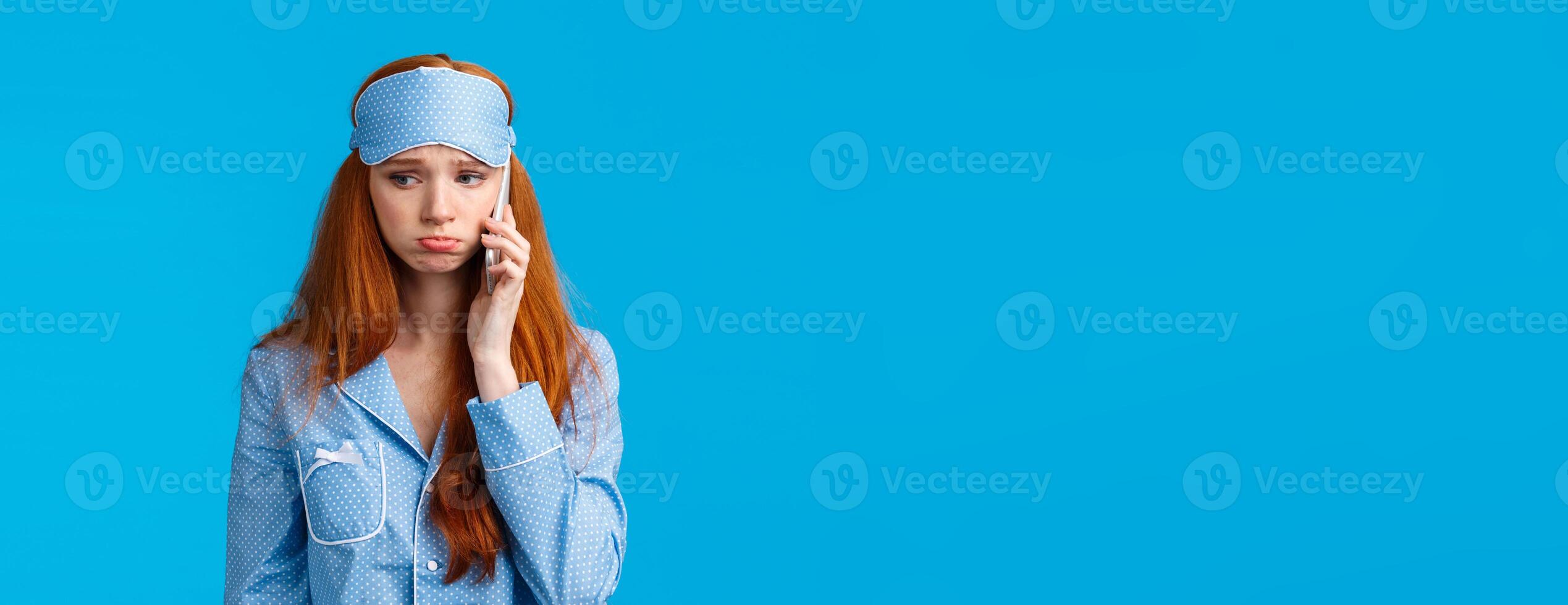 Sulky and gloomy upset cute silly redhead girl calling girlfriend talking about problems, had bad dream, holding smartphone near ear, having phone call in nightwear and sleep mask photo