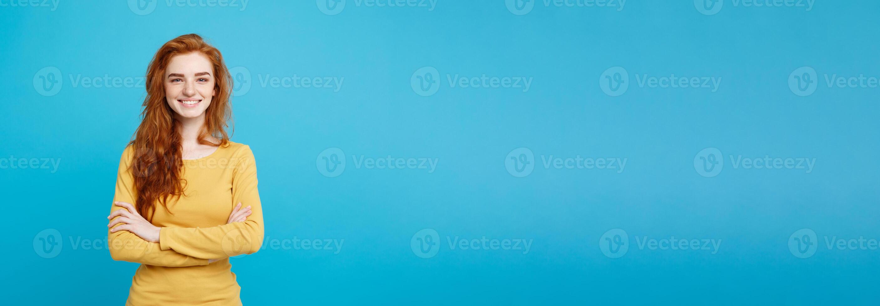 Portrait of young beautiful ginger woman with freckles cheerfuly smiling looking at camera. Isolated on pastel blue background. Copy space. photo