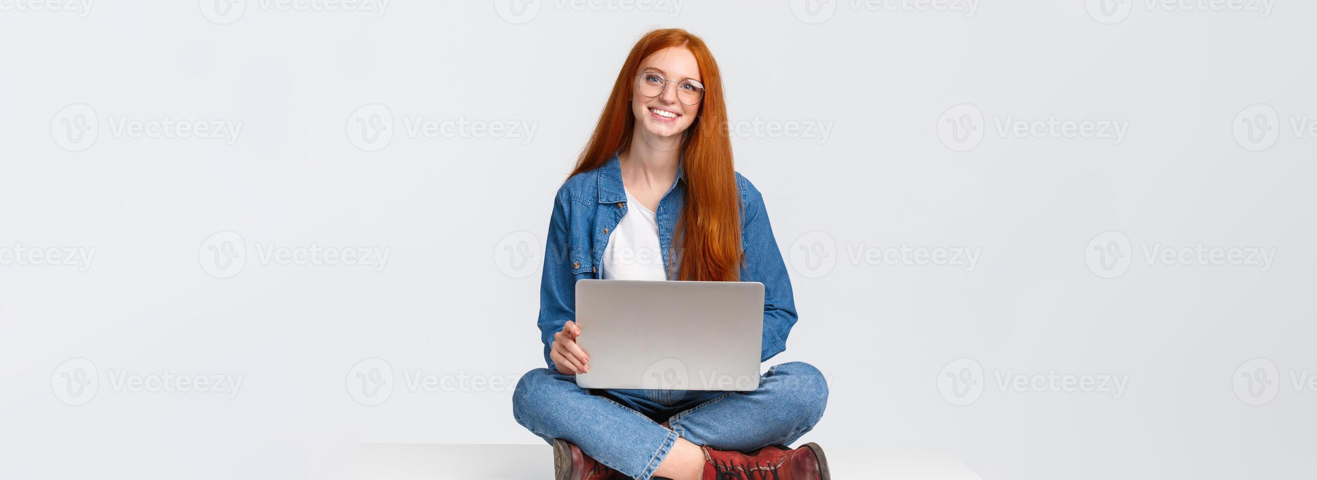 Attractive charismatic redhead caucasian female sit on floor with crossed legs, holding laptop laps, working on fresh air, writing new program, freelancing over white background photo