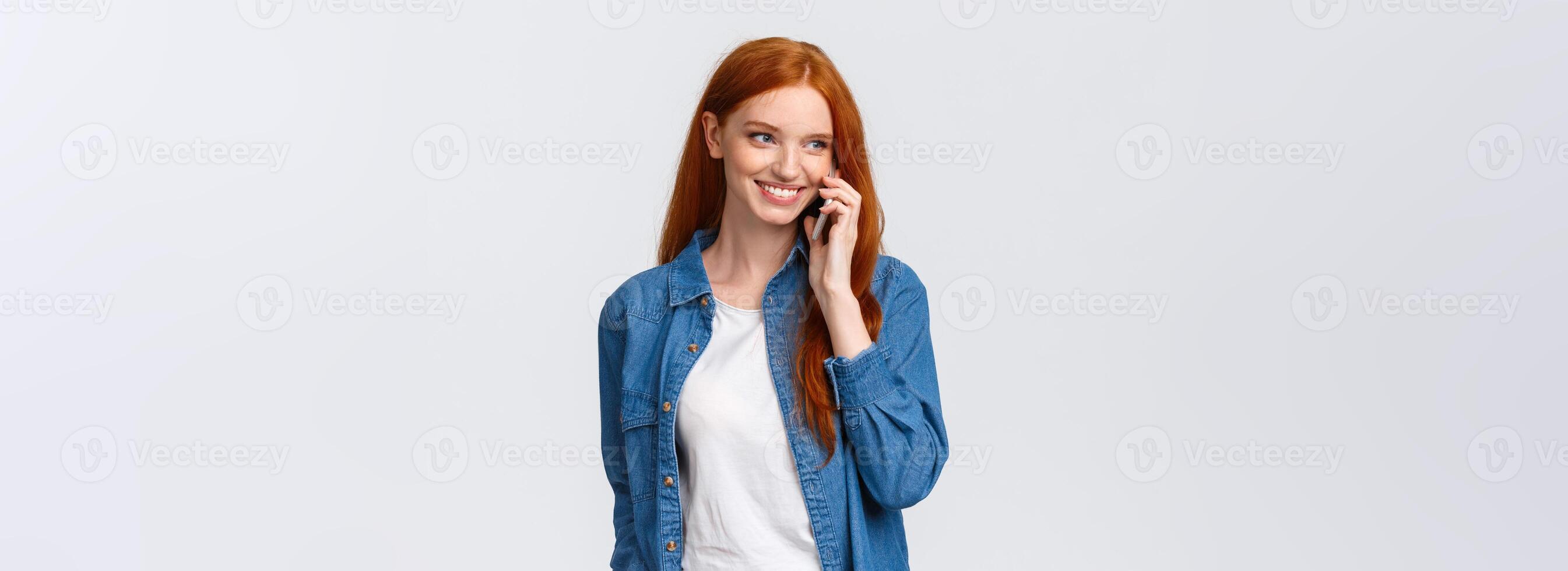 Girl calling boyfriend pick her up after classes. Attractive outgoing redhead woman talking on phone, smiling carefree, look away as having casual conversation on smartphone, white background photo