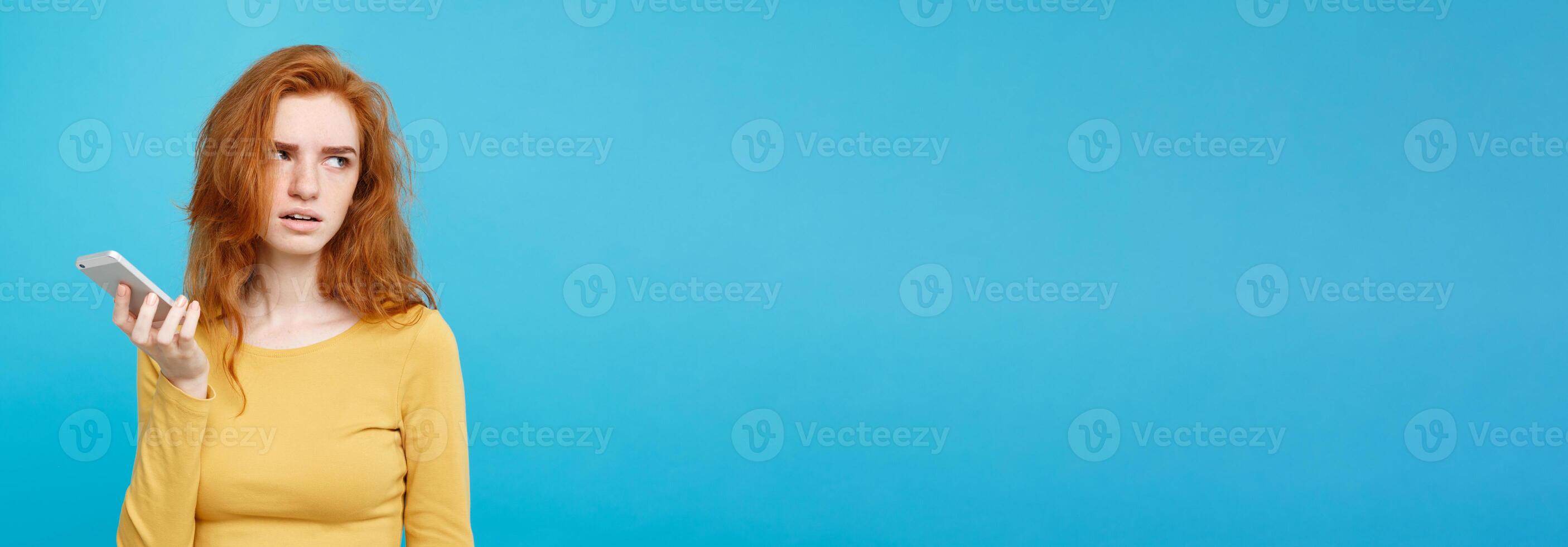 Lifestyle and Technology concept - Portrait of cheerful happy ginger red hair girl with joyful and exciting smiling to camera. Isolated on Blue Pastel Background. Copy space. photo