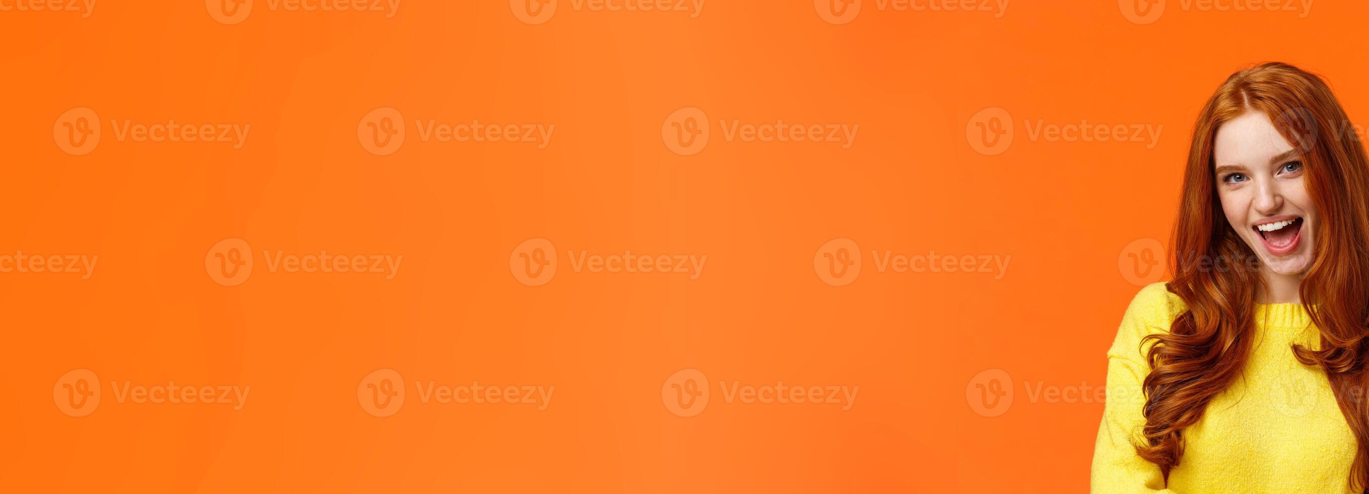 Sassy and daring cool redhead girl with curls, showing okay excellent gesture and smiling excited, assure party be awesome, give permission, say yes, confirm or recommend something, orange background photo