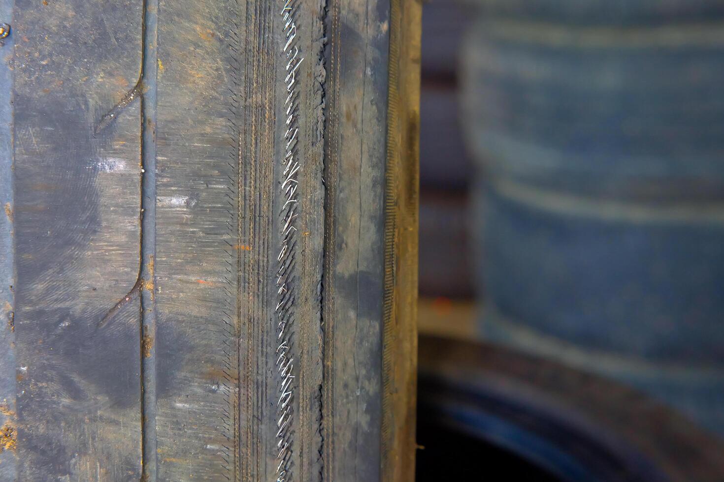 Old car tire in the garage, closeup of photo with selective focus.Tires are damaged and expired. If you see a wire, they should be replaced immediately.