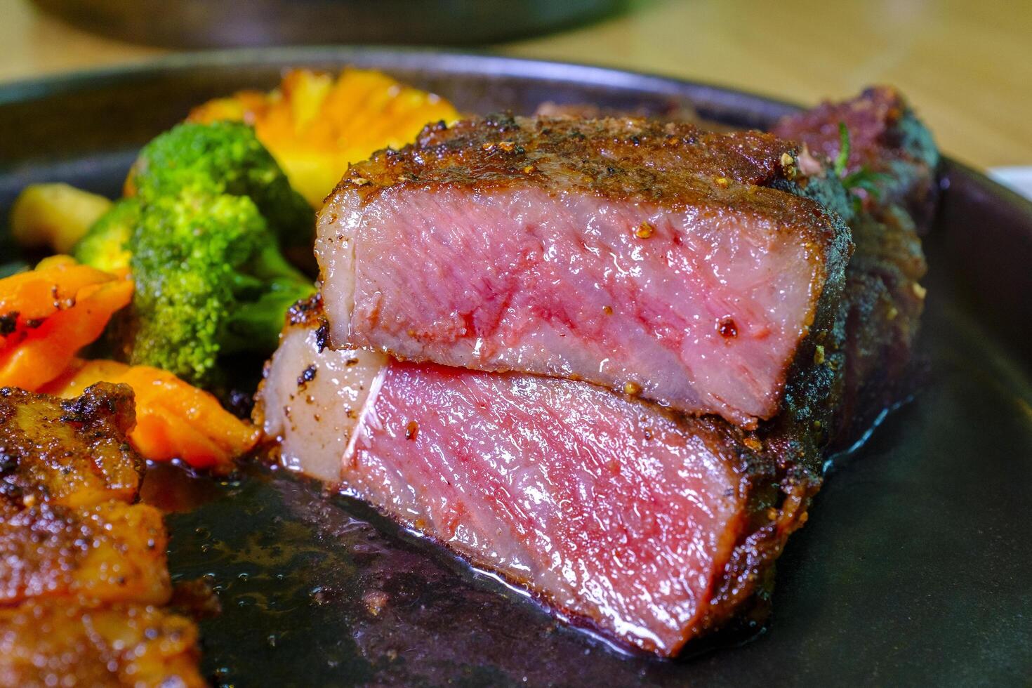 Closeup Juicy Beef Steak Medium Rare on a plate, ready to eat.Grilled beef steak with vegetables on a hot plate, close up photo