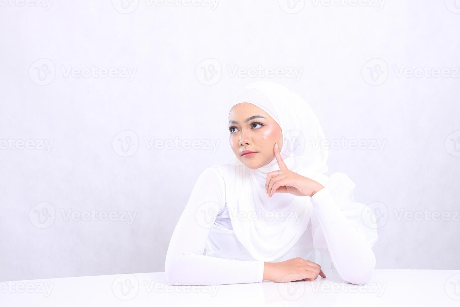 portrait charm Young girl hijab beautiful elegant look right hand on white table and touch left cheek isolated white background. concept of cosmetics, spa, skin care, Facial treatment photo