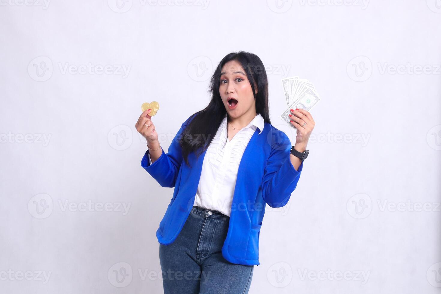Elegant mature office woman wearing blue formal suit standing surprised to camera hand holding dollar money and bitcoin isolated white background. for transaction, investment, business content photo