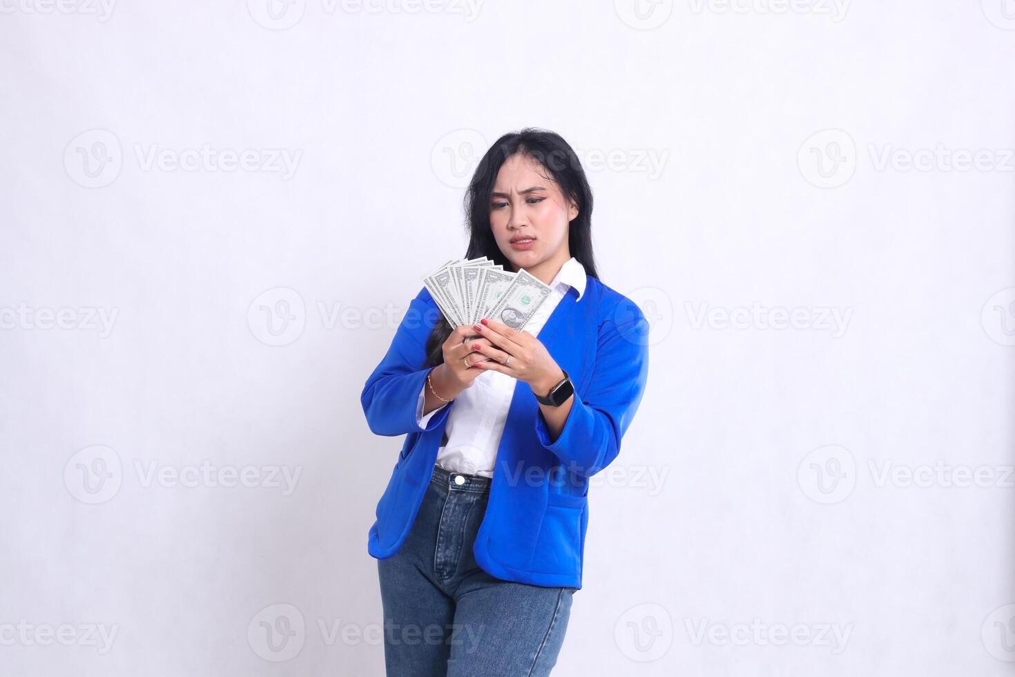 beautiful mature office woman wearing blue formal suit standing annoyed to dollar both hands holding dollar bills in front of white background isolation. for transaction, finance, business content photo