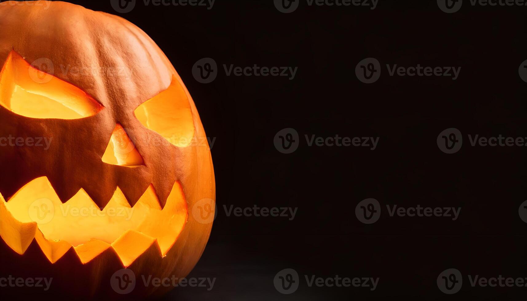 part of a pumpkin carved into a classic jack-o'-lantern with a menacing face, glowing brightly from within, set against a stark black background for dramatic effect. photo
