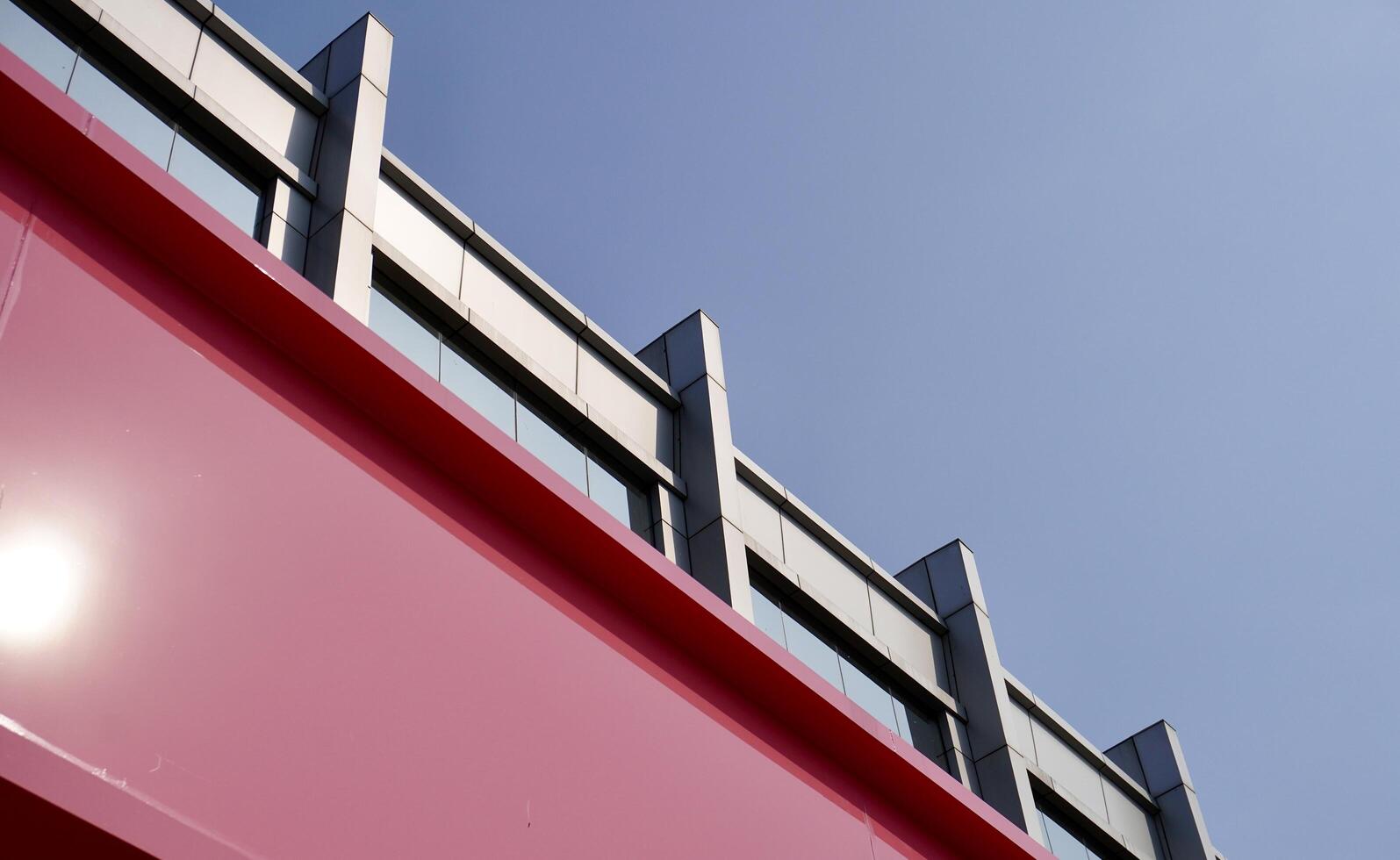 Wide and tall pink and gray shophouse building exterior with windows structure isolated on horizontal ratio outdoor blue sky background. photo