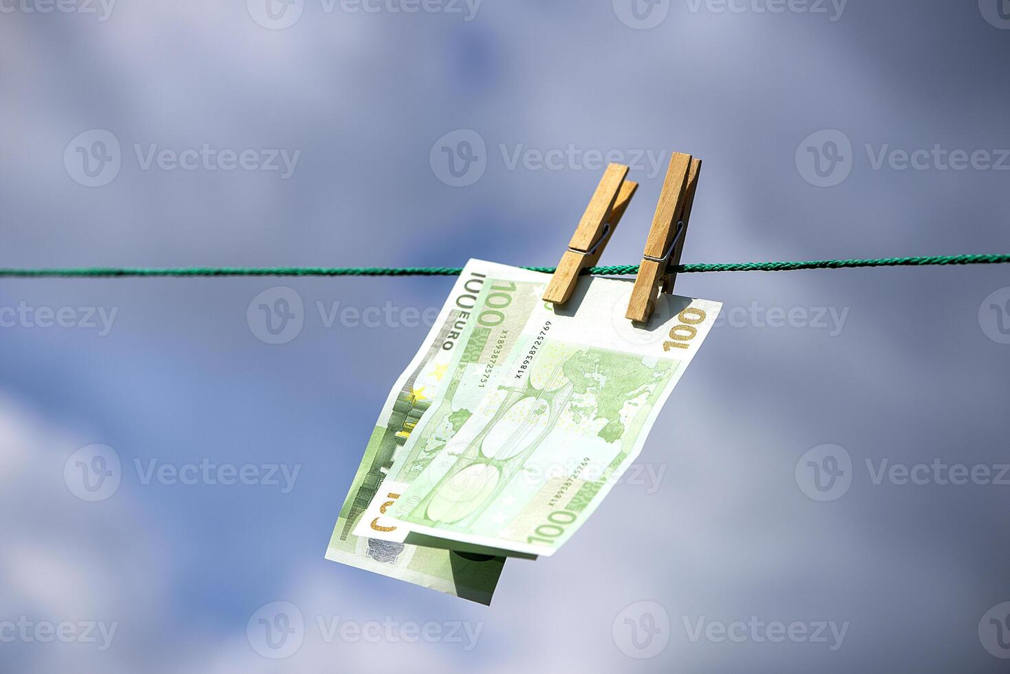 hundred euro paper bills are pinned to a string with clothespins photo